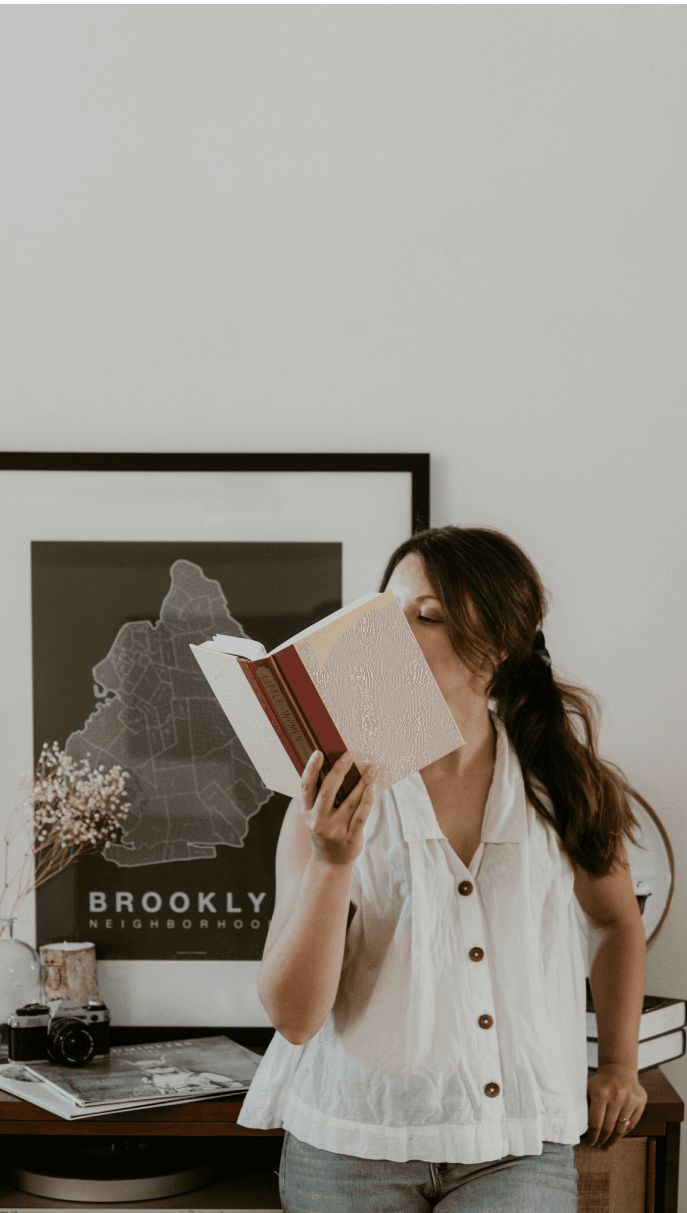 Emily reading a book leaning up against a console