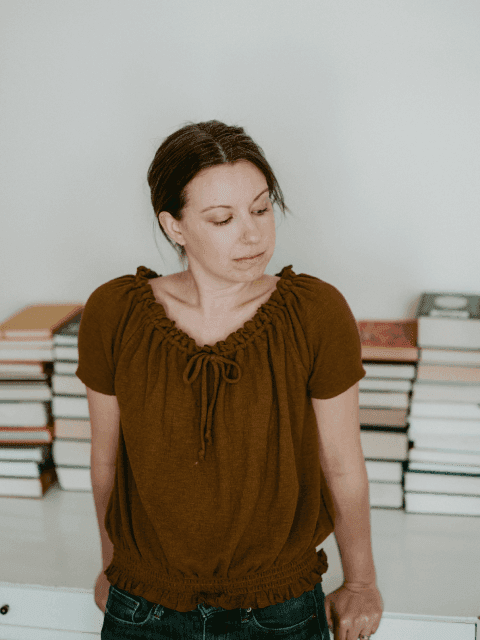 Emily leaning up against desk with books in the background