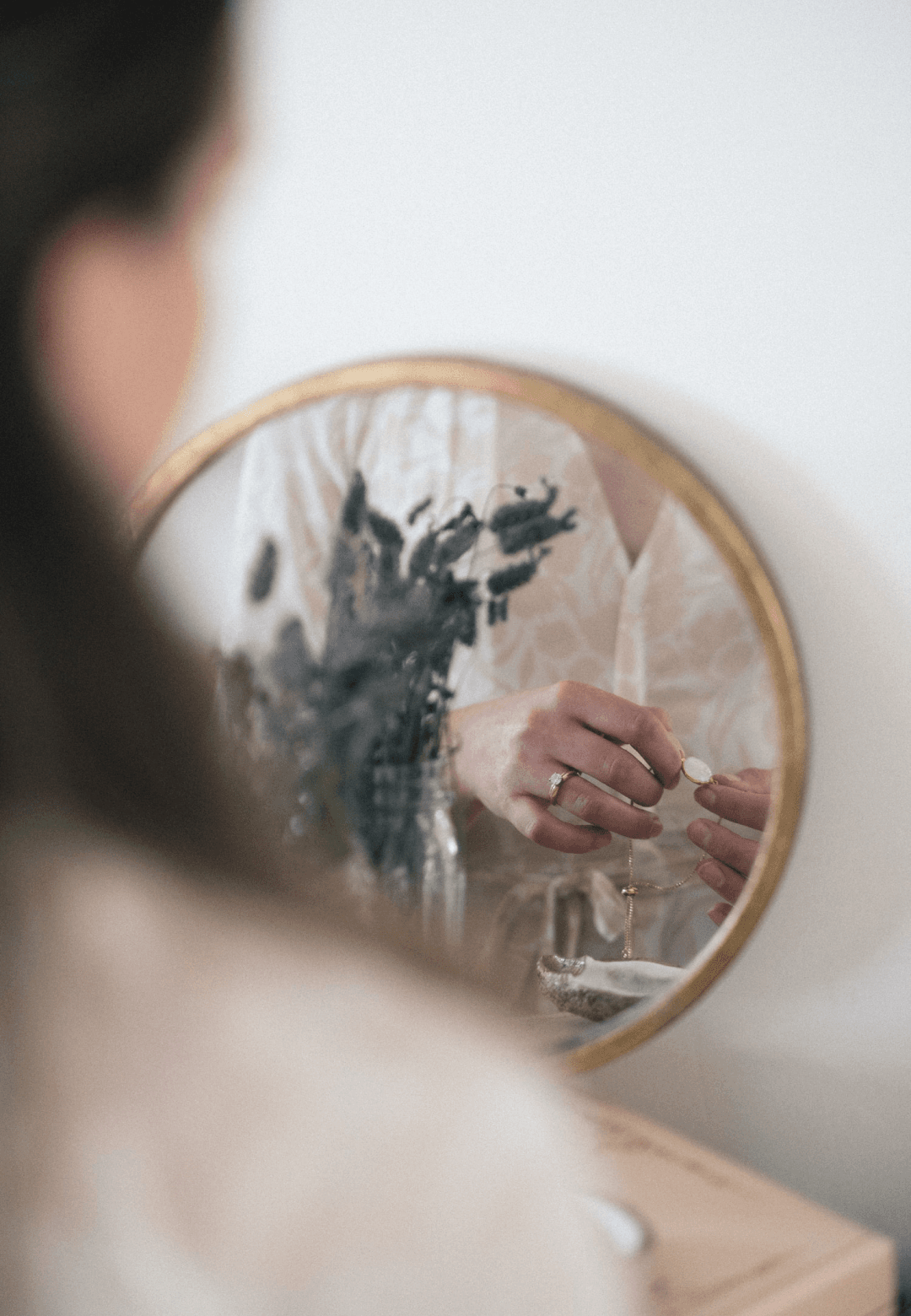 Emily putting on necklace in mirror