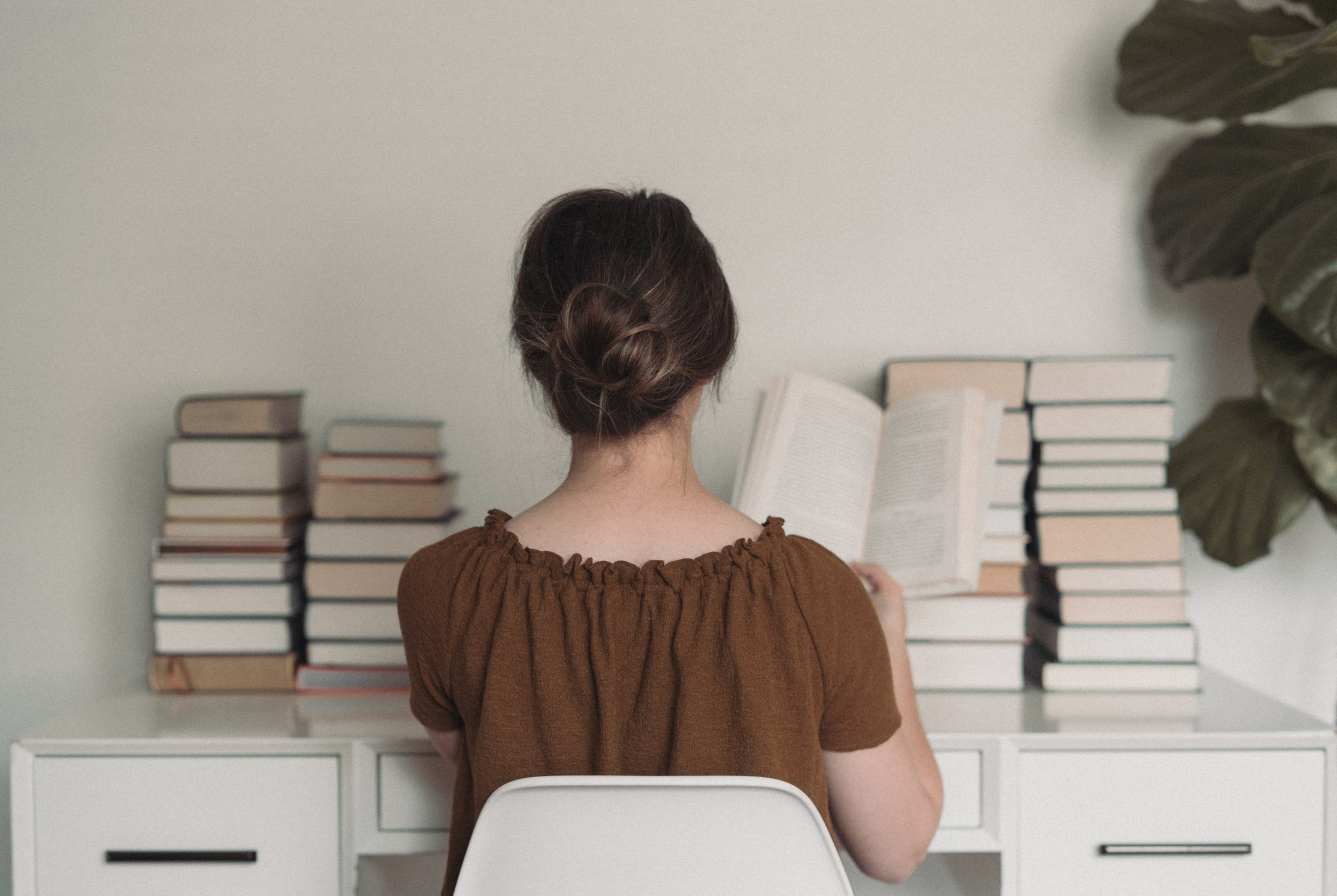 Emily leaning up against desk with books behind her