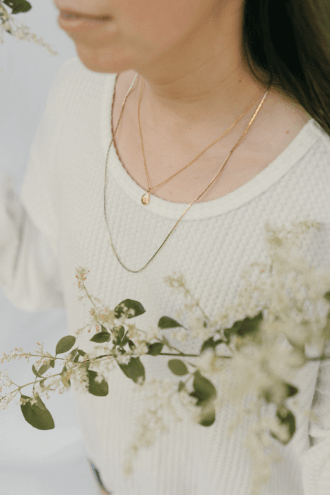 Closeup of Emily wearing jewelry with olive branch