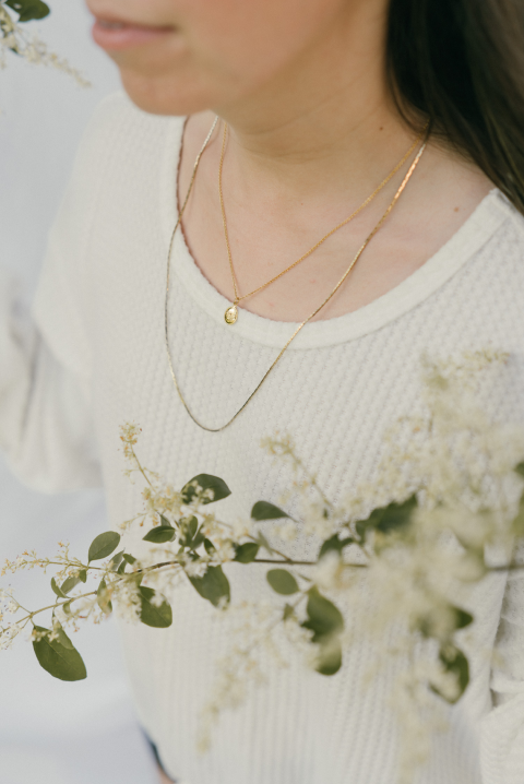 Closeup of Emily wearing jewelry with olive branch